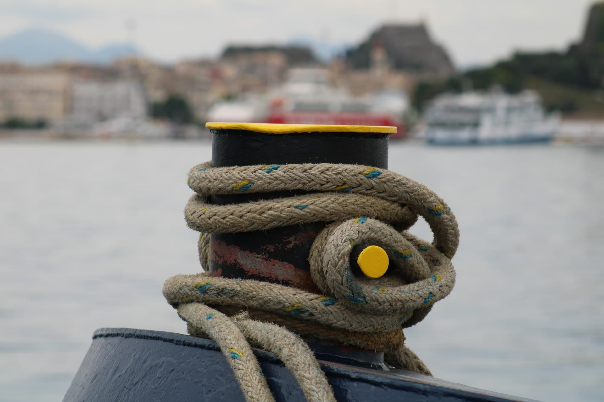 Mooring rope coiled around a bollard with the harbor behind